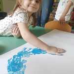 dzieci wykonują odciski dłoni niebieską farbą
