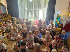 Dzieci ubrane w kolorowe kropki siedzą na dywanie.jpg
