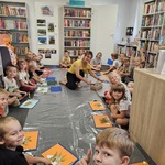Dzieci wykonują prace plastyczne na dywanie w bibliotece.jpg
