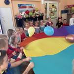 Dzieci podrzucają kolorowe balony na chuście animacyjnej tak, żeby z niej nie spadły.