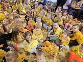 Dzieci w żółtych koszulkach siedzą na dywanie.jpg
