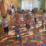 Dzieci tańczą w rytm muzyki trzymając w dłoniach kolorowe serduszka.
