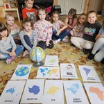 Dzieci siedzą na dywanie i oglądają obrazki kontynentów.jpg