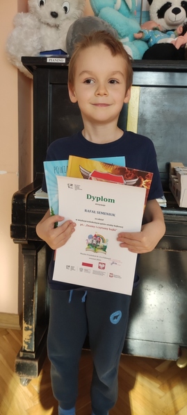 Chłopiec trzyma dyplom za udział w konkursie.jpg