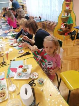 Dzieci wraz z rodzicami wykonują ozdoby świąteczne z różnorodnych materiałów plastycznych.