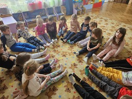 Dzieci siedzą w kole i prezentują kolorowe skarpetki.jpg